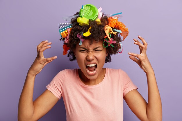 Mujer joven con corte de pelo afro y desechos plásticos en su cabello