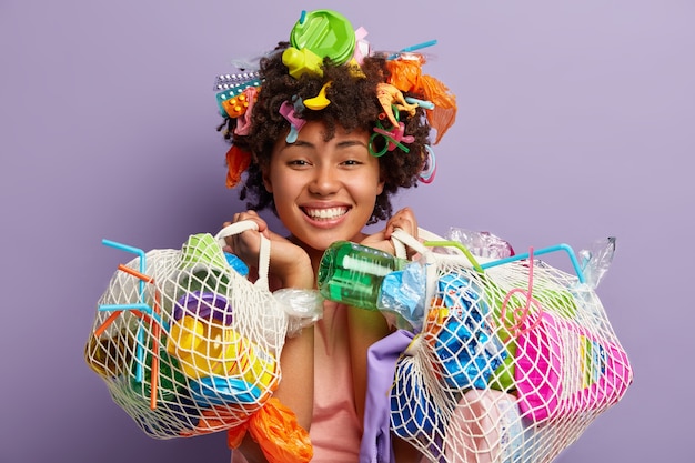 Mujer joven con corte de pelo afro y desechos plásticos en su cabello