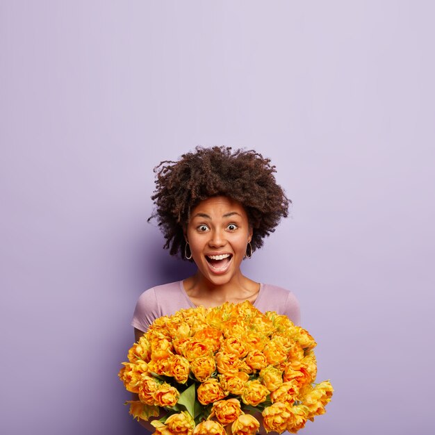 Mujer joven con corte de pelo afro con ramo de flores amarillas