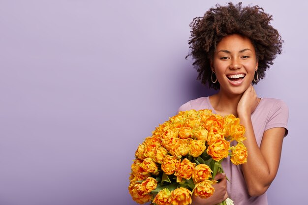 Mujer joven con corte de pelo afro con ramo de flores amarillas