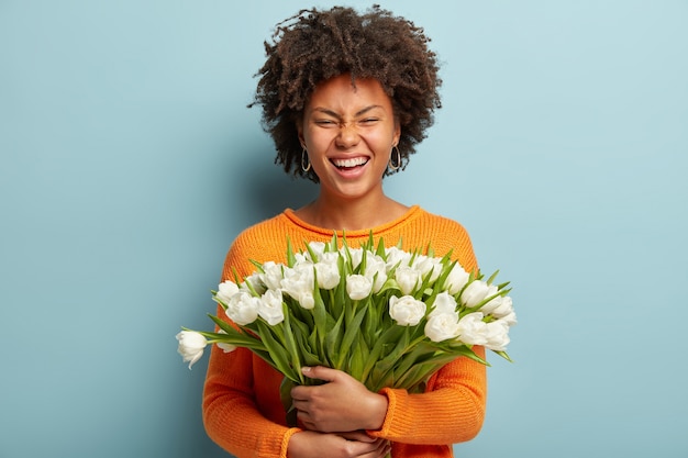 Mujer joven con corte de pelo afro con ramo de flores blancas