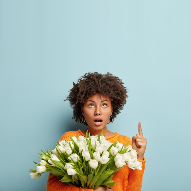 Mujer joven con corte de pelo afro con ramo de flores blancas