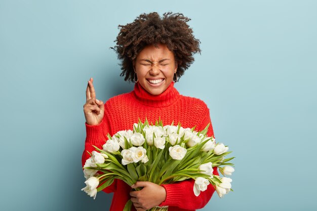 Mujer joven con corte de pelo afro con ramo de flores blancas
