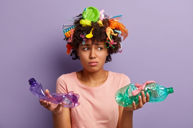 Mujer joven con corte de pelo afro y residuos plásticos en el cabello