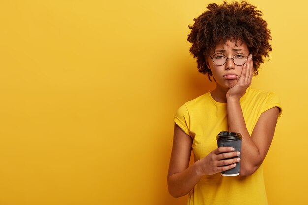 Mujer joven con corte de pelo afro sosteniendo una taza de café