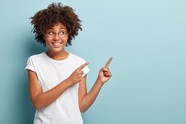 Mujer joven con corte de pelo afro vistiendo camiseta blanca