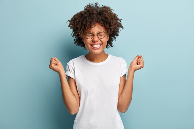 Mujer joven con corte de pelo afro vistiendo camiseta blanca