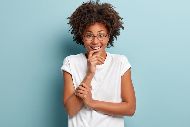 Mujer joven con corte de pelo afro vistiendo camiseta blanca