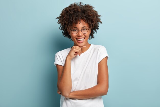 Mujer joven con corte de pelo afro vistiendo camiseta blanca