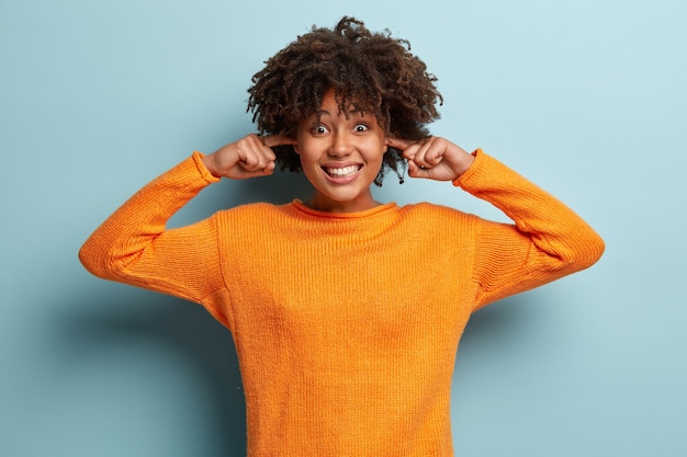 Mujer joven con corte de pelo afro vistiendo jersey naranja