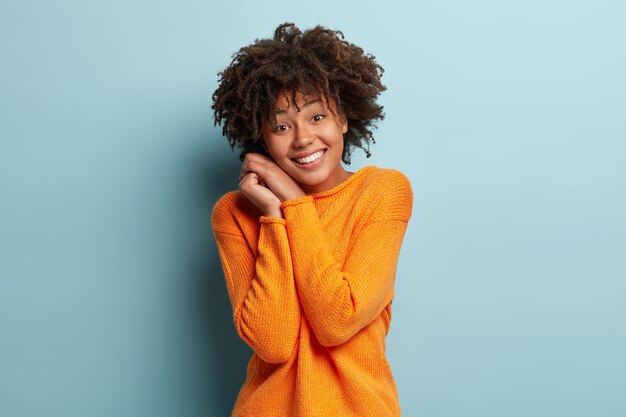 Mujer joven con corte de pelo afro vistiendo jersey naranja