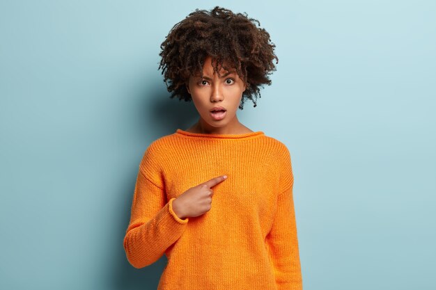 Mujer joven con corte de pelo afro vistiendo jersey naranja