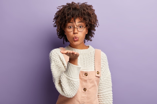 Mujer joven con corte de pelo afro vistiendo monos y suéter