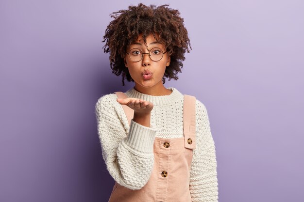 Mujer joven con corte de pelo afro vistiendo monos y suéter