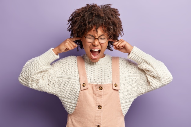 Mujer joven con corte de pelo afro vistiendo monos y suéter