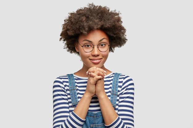 Mujer joven con corte de pelo afro vistiendo overoles de mezclilla