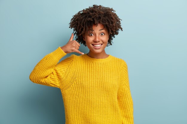 Mujer joven con corte de pelo afro vistiendo suéter amarillo