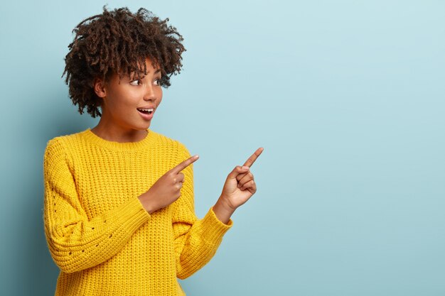 Mujer joven con corte de pelo afro vistiendo suéter amarillo