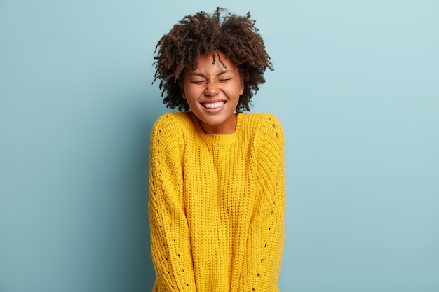 Mujer joven con corte de pelo afro vistiendo suéter amarillo