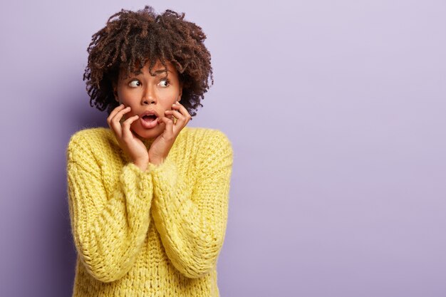 Mujer joven con corte de pelo afro vistiendo suéter amarillo