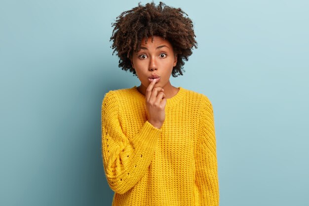 Mujer joven con corte de pelo afro vistiendo suéter amarillo