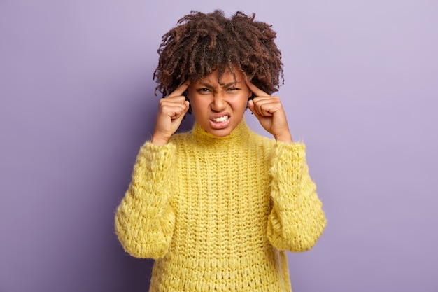 Mujer joven con corte de pelo afro vistiendo suéter amarillo