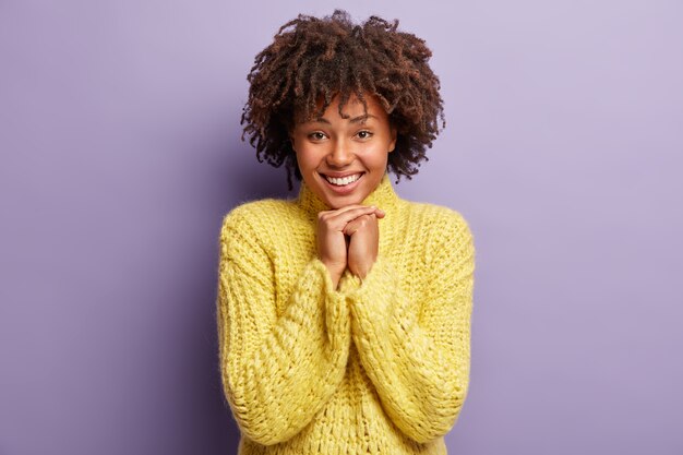 Mujer joven con corte de pelo afro vistiendo suéter amarillo