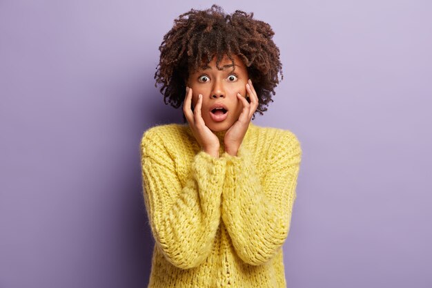 Mujer joven con corte de pelo afro vistiendo suéter amarillo