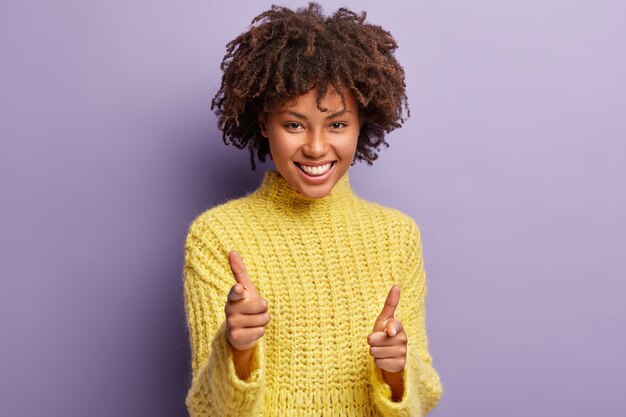 Mujer joven con corte de pelo afro vistiendo suéter amarillo