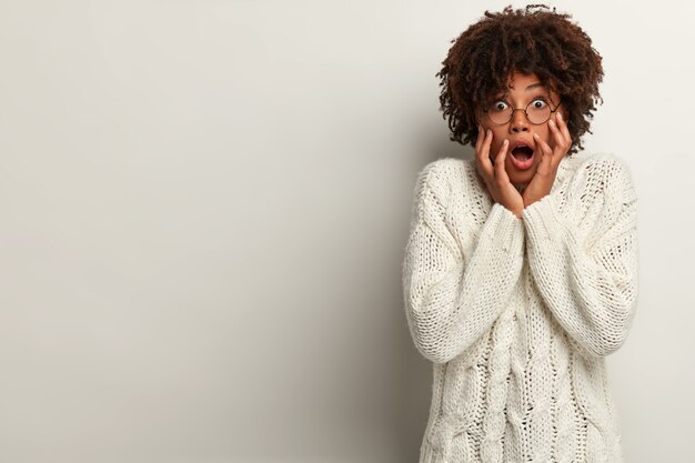 Mujer joven con corte de pelo afro vistiendo suéter blanco