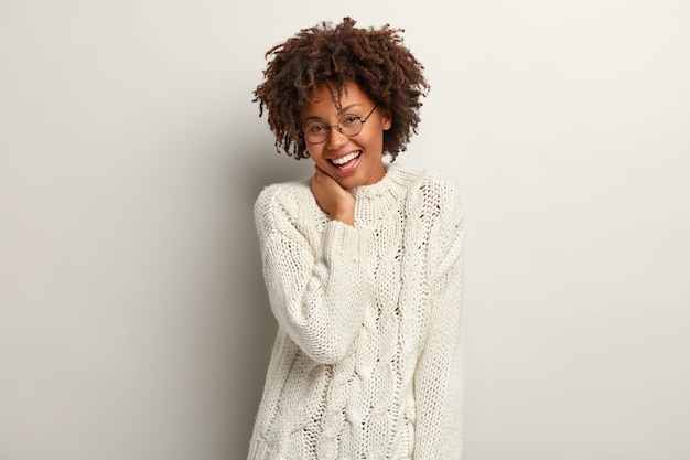 Mujer joven con corte de pelo afro vistiendo suéter blanco