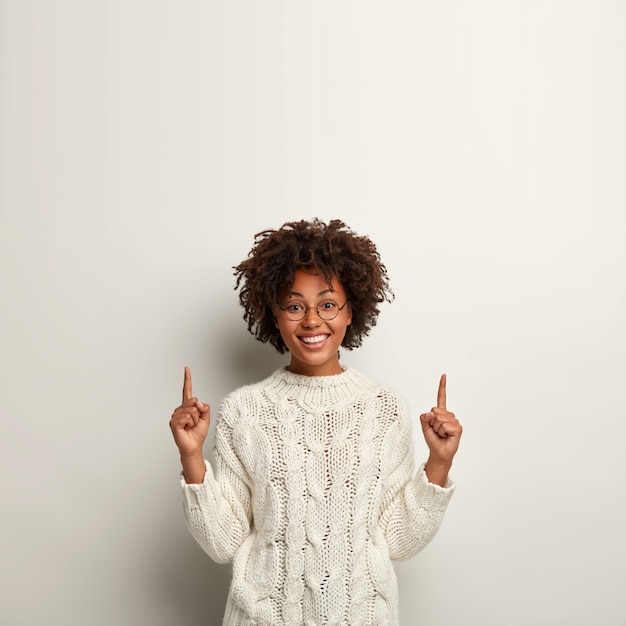 Mujer joven con corte de pelo afro vistiendo suéter blanco