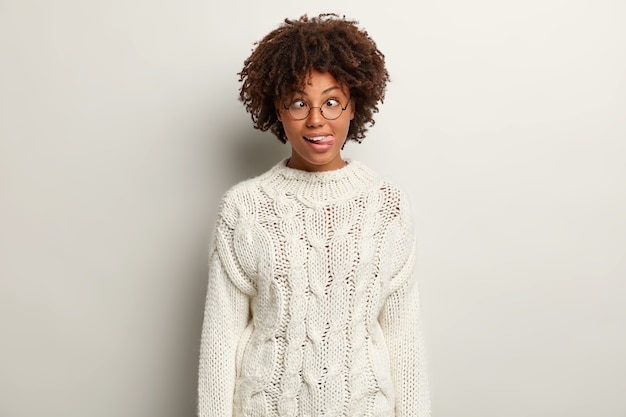 Mujer joven con corte de pelo afro vistiendo suéter blanco