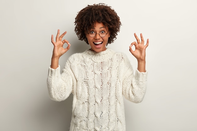 Mujer joven con corte de pelo afro vistiendo suéter blanco