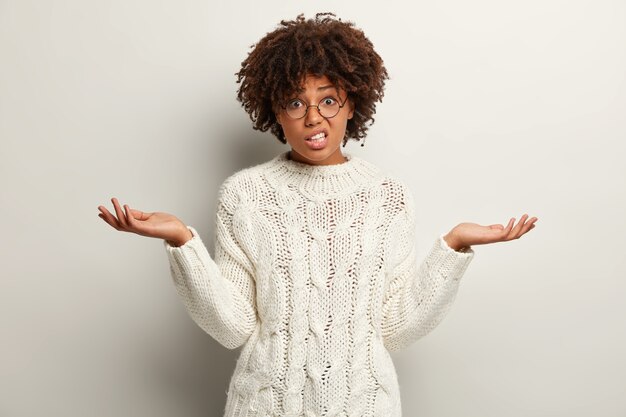 Mujer joven con corte de pelo afro vistiendo suéter blanco