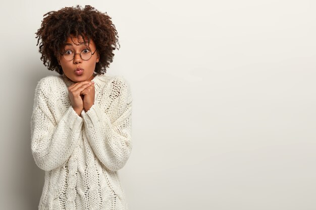 Mujer joven con corte de pelo afro vistiendo suéter blanco