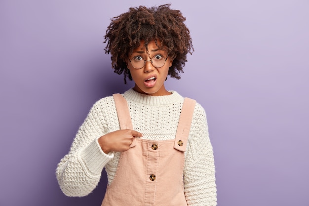 Mujer joven con corte de pelo afro vistiendo suéter y general rosa