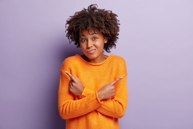 Mujer joven con corte de pelo afro vistiendo suéter naranja