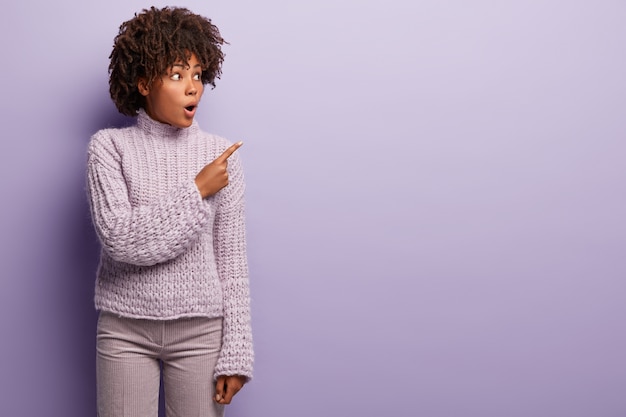 Mujer joven con corte de pelo afro vistiendo suéter púrpura