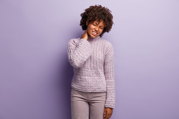 Mujer joven con corte de pelo afro vistiendo suéter púrpura