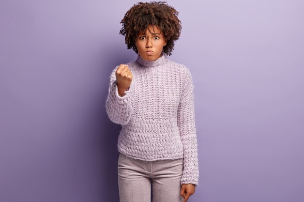 Mujer joven con corte de pelo afro vistiendo suéter púrpura