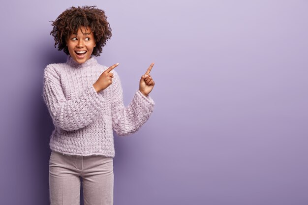 Mujer joven con corte de pelo afro vistiendo suéter púrpura