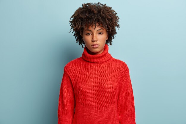 Mujer joven con corte de pelo afro vistiendo suéter rojo