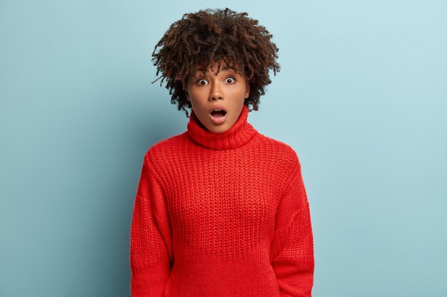 Mujer joven con corte de pelo afro vistiendo suéter rojo