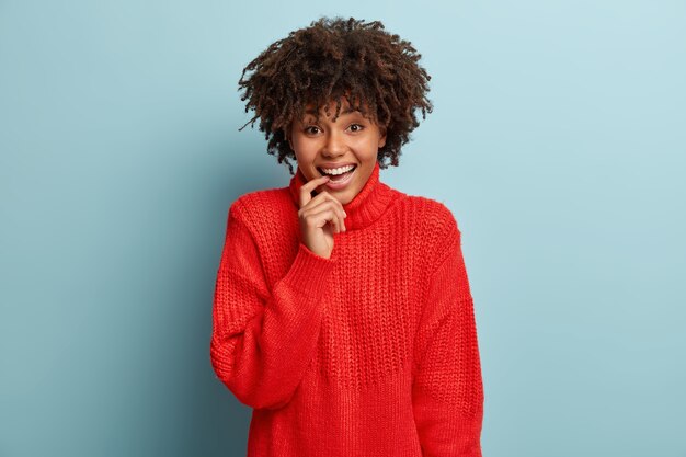 Mujer joven con corte de pelo afro vistiendo suéter rojo