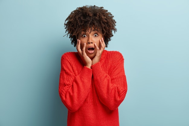 Mujer joven con corte de pelo afro vistiendo suéter rojo