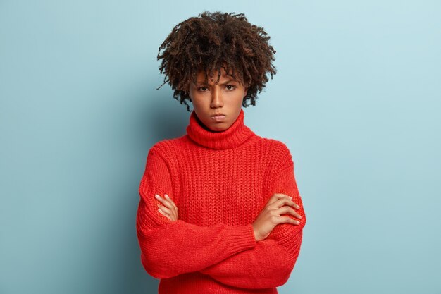 Mujer joven con corte de pelo afro vistiendo suéter rojo