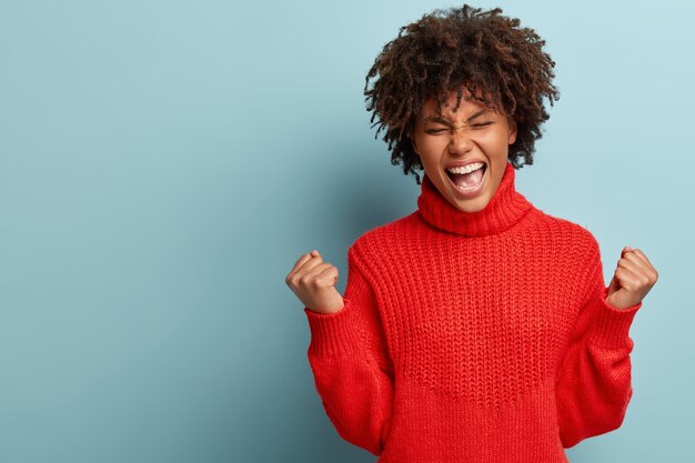 Mujer joven con corte de pelo afro vistiendo suéter rojo