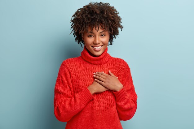 Mujer joven con corte de pelo afro vistiendo suéter rojo