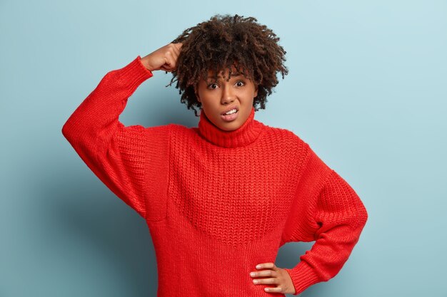 Mujer joven con corte de pelo afro vistiendo suéter rojo